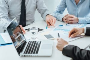 3 אנשים בישיבה עסקית וביניהם שולחן לבן עם מסמכים ולפטופ - תמונת רקע לקורס ניהול פיננסי וניתוח דוחות כספיים - להב הכשרת מנהלים